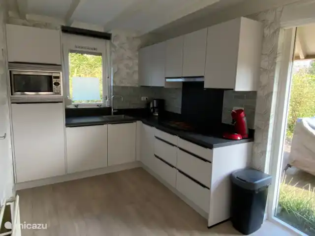 De open keuken is functioneel ingericht en heeft een combi magnetron, een keramische kookplaat, koffiezetapparaat en waterkoker, een tosti ijzer, een broodrooster en in de bijkeuken staat de vaatwasser, een wasmachine en een droger.